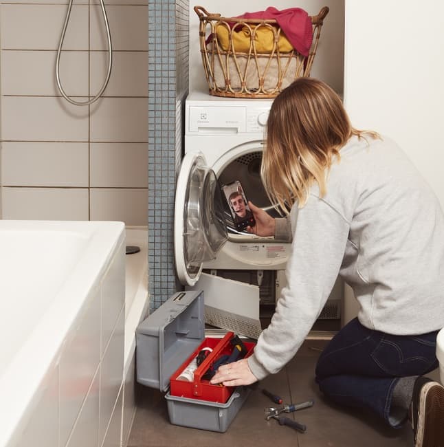  photo d’une personne réparant un lave-linge d’occasion avec l’assistance dépannage à distance youzd 