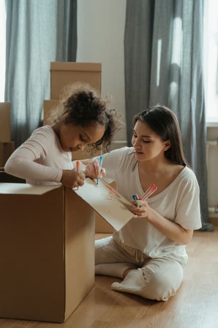 Photo d'une femme et de son enfant dans un carton de déménagement.